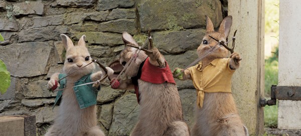 Still frame from film of Peter Rabbit showing the rabbits aiming slingshots