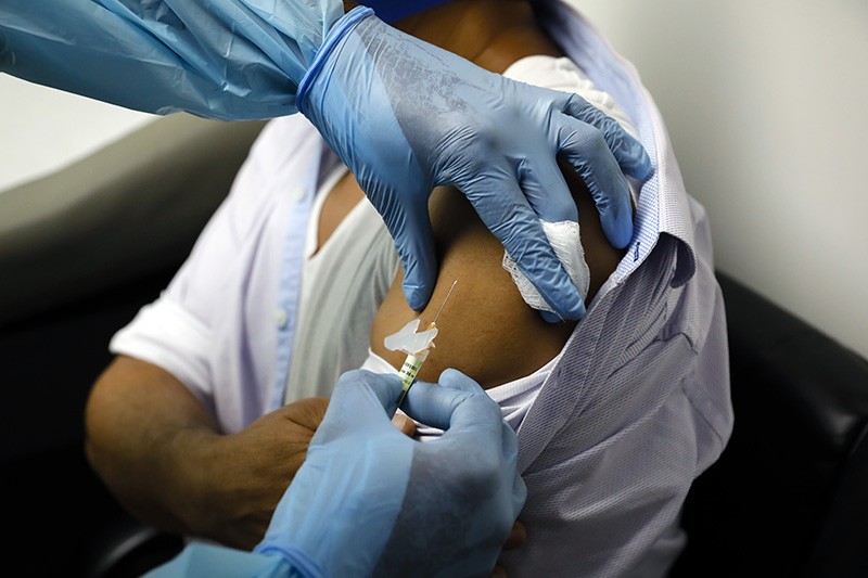 A health worker injects a Covid-19 vaccine into a person during clinical trials