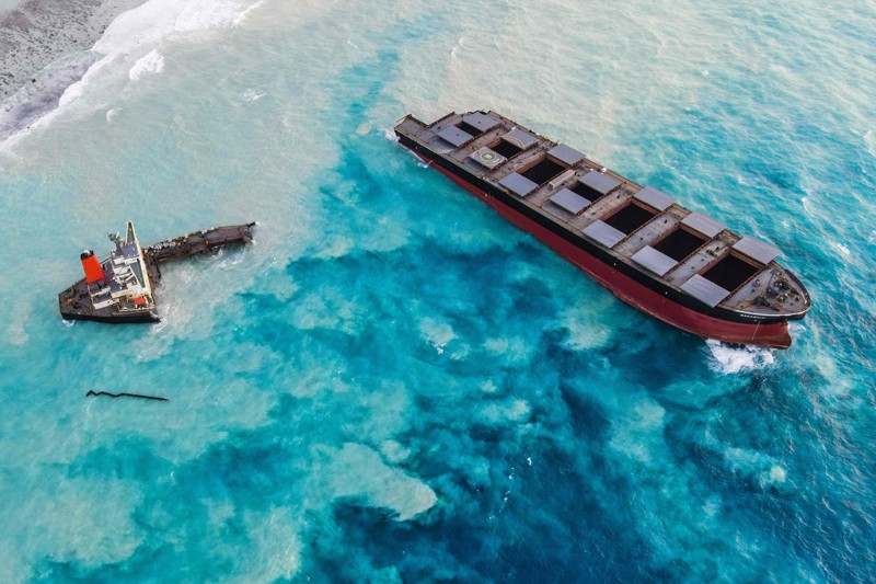 Aerial view of a bulk carrier that has run aground and split into two sections, spilling oil into the surrounding ocean