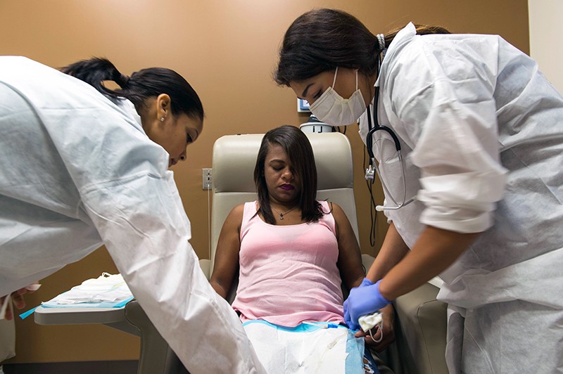 A woman is treated by two nurses.