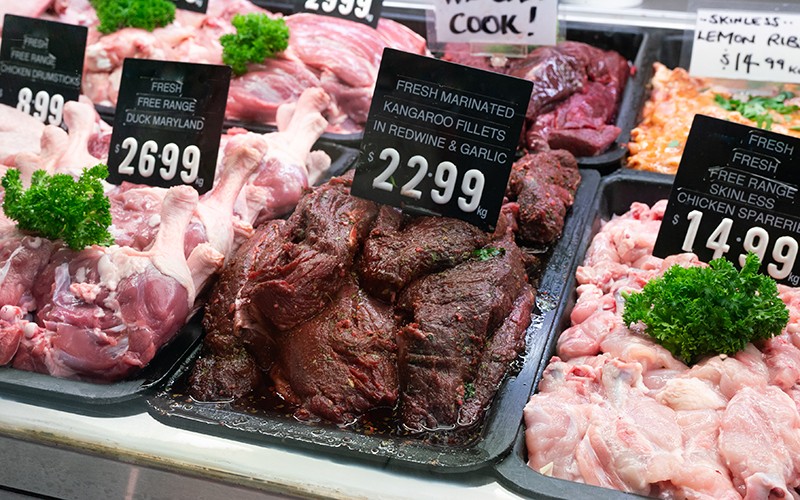Kanagroo meat sits in a tray next to other meat in a butcher shop display