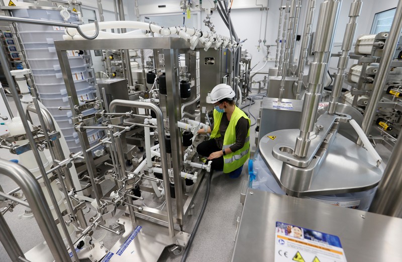 Worker in a hard hat and hi-vis vest setting up a vaccine production line in a factory in Switzerland