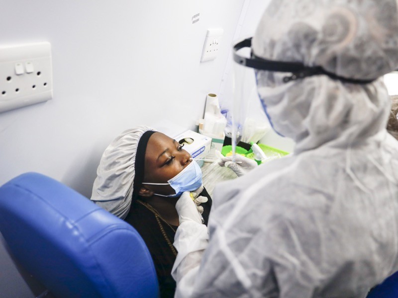 A passenger receives a nasal swab from a healthcare worker in SA testing mobile unit.