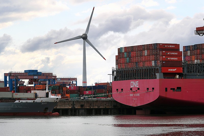 A wind turbine and a loaded cargo ship at the Port of Hamburg, Germany