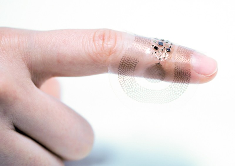 Close up of a clear, flexible, sticking plaster-like device resting on someones forefinger