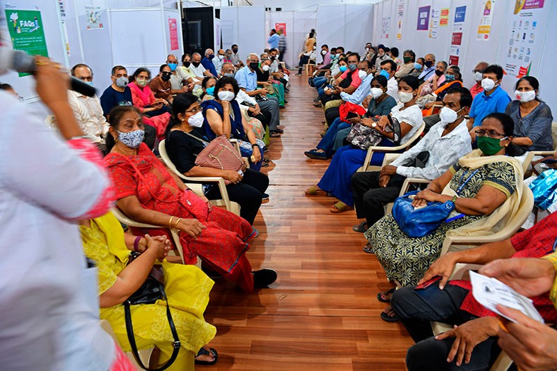 People listen to a medical staff as they wait to receive the Covid-19 coronavirus vaccine at a vaccination centre in Mumbai