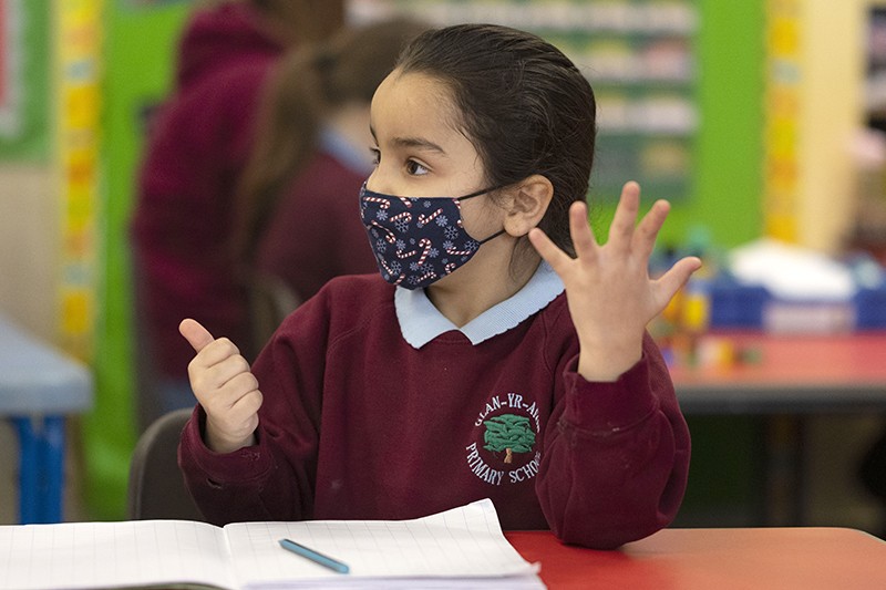 A child wearing a face mask counts during a maths lesson in a classroom in Wales