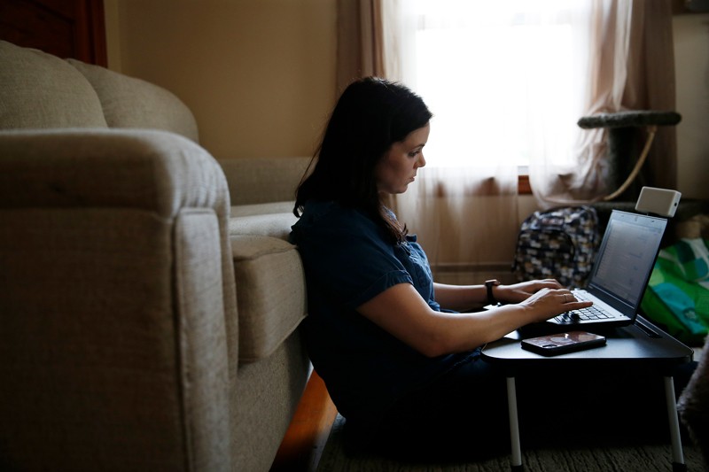 A woman suffering from symptoms of "long COVID" working on a laptop in her living room