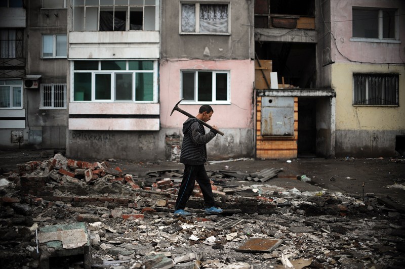 A Roma man walks with a pickaxe in the remains of a demolished house in a Roma suburb in the city of Plovdiv, Bulgaria