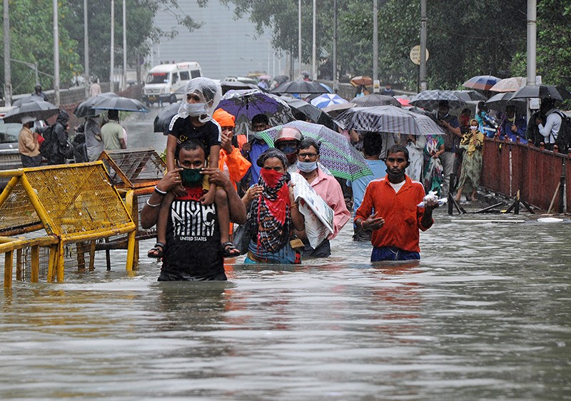 Groups of people wade through waist deep water from flooding in Mumbai, India