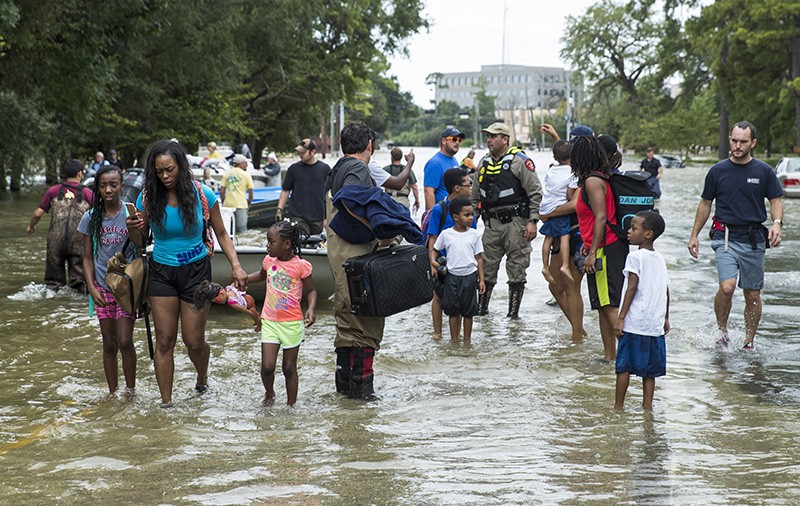 Families walk out of the water in the Energy Corridor of west Houston due to flooding from Hurricane Harvey