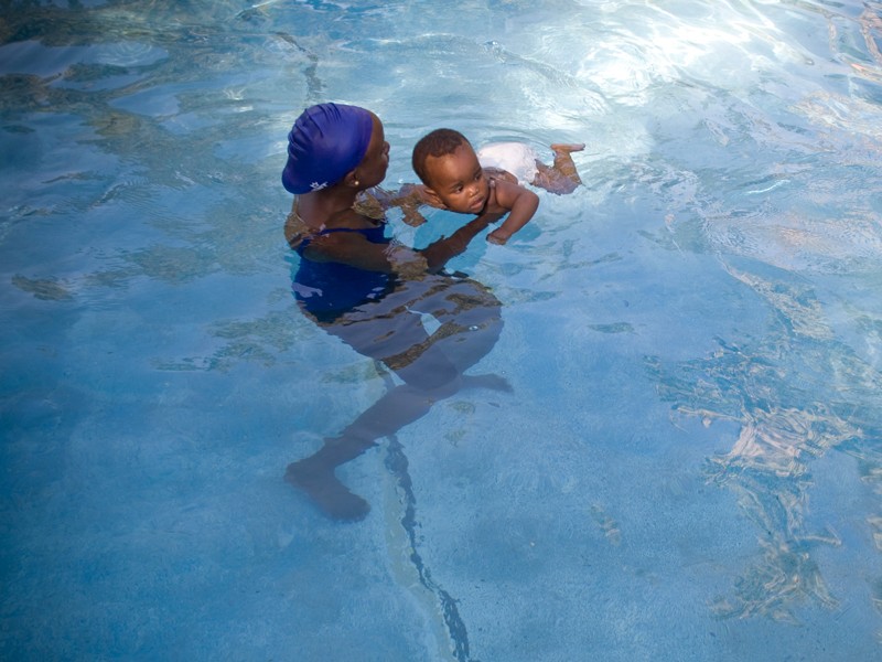 Student from Waterford Kamhlaba college swimming with an orphaned child, in a Swaziland hospital..