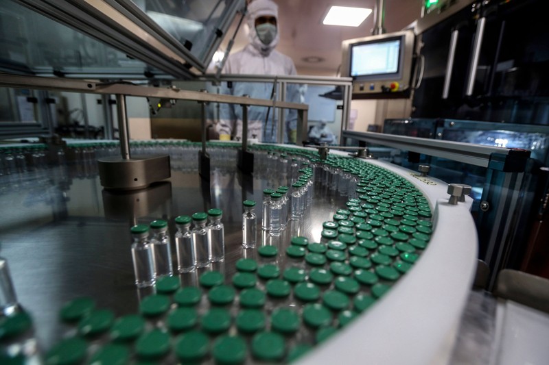 Vials move past on the conveyor belt of a filing machine at a facility producing COVID-19 vaccine in Pune, India