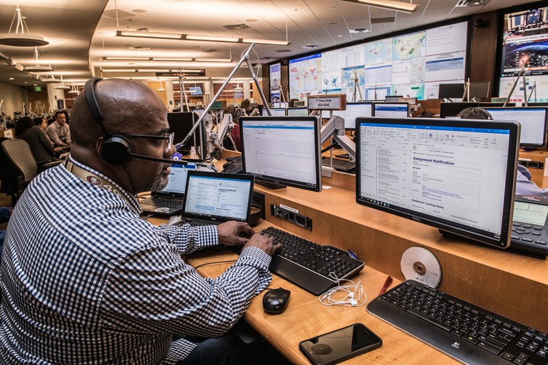 A worker sits as a desk looking at multiple monitors in the CDC Emergency Operations Center