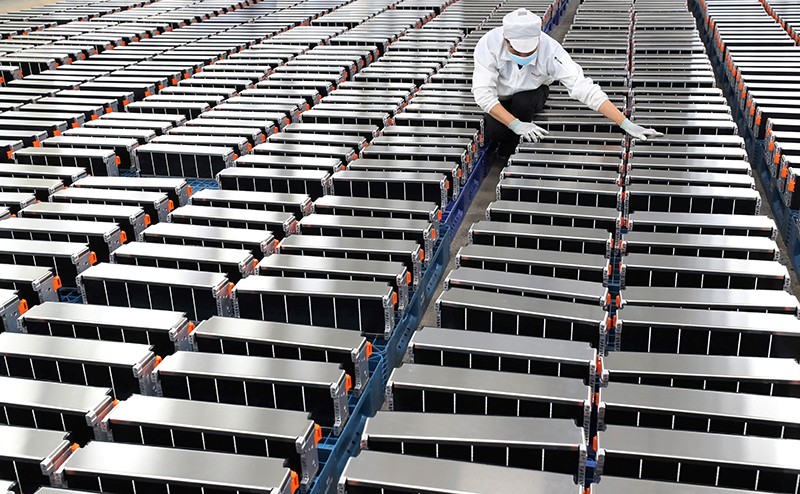 A worker stands amid rows of large lithium batteries