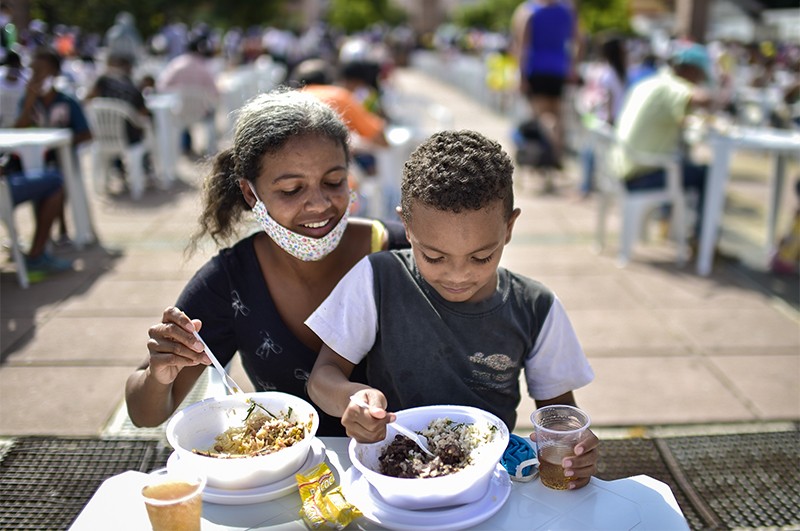 A mother and her son eat a meal at an open-air restaurant in Belo Horizonte
