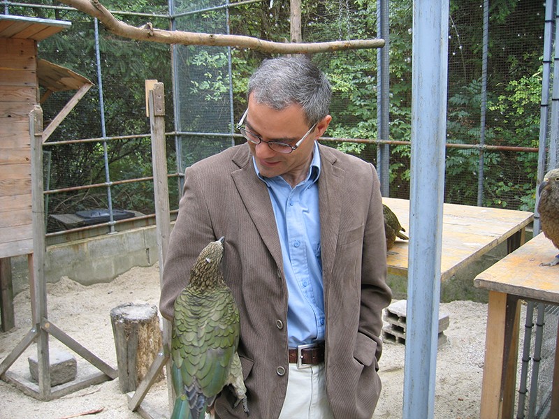 Kevin Laland with a bird in an outdoor cage setting.