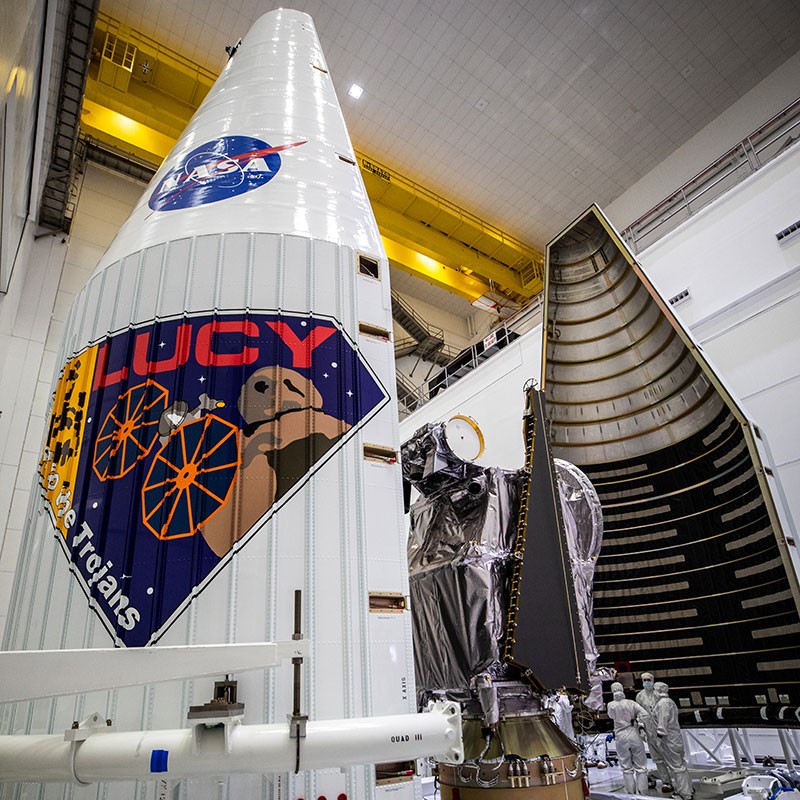Workers move the first half of the ULA payload fairing toward NASA’s Lucy spacecraft.