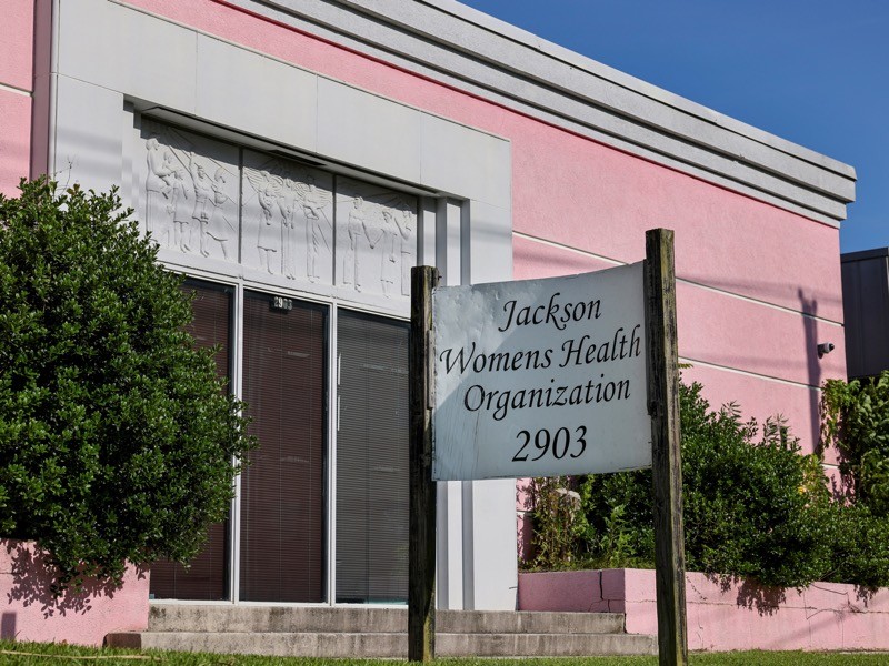 A pink building with a sign reading 'Jackson Womens Health Organization'.