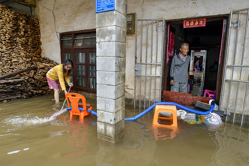 A house in Hainan, China, with a pipe to pump water from the interior and deposit it into murky floodwater outside.