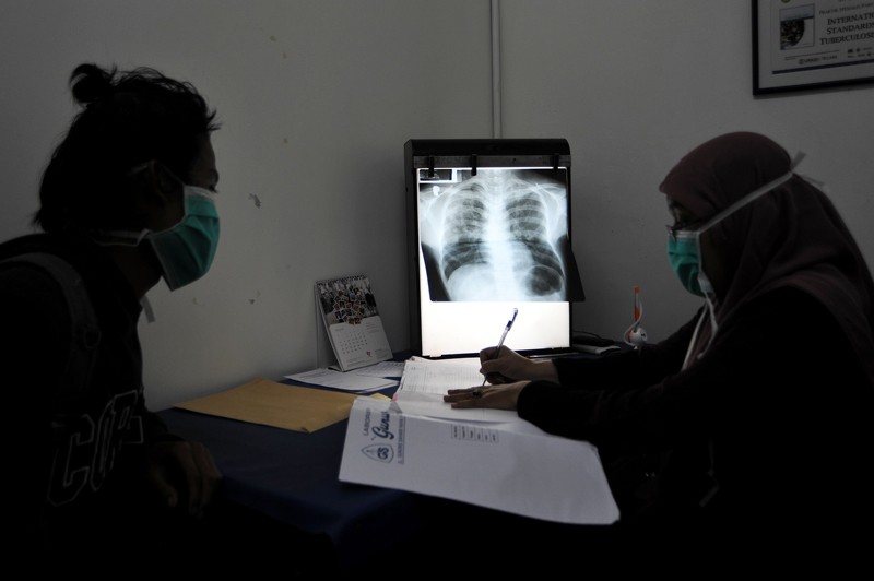 A doctor writes notes while checking the condition of her patient