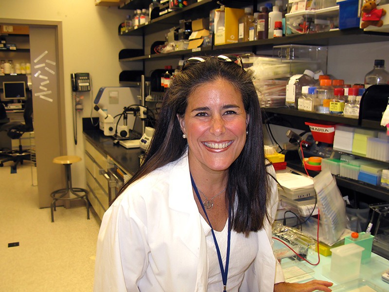 Maria Morasso smiling at the camera in a full laboratory