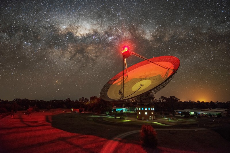 Parkes radio telescope photographed at night against the Milky Way illuminated by a red light