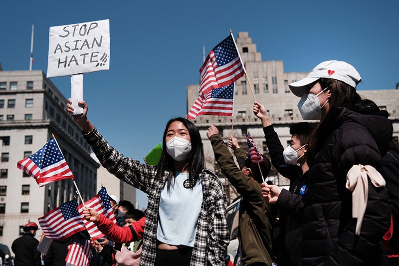People protest anti-Asian hate and the rise in hate crimes with signs and US flags at a march in New York City.