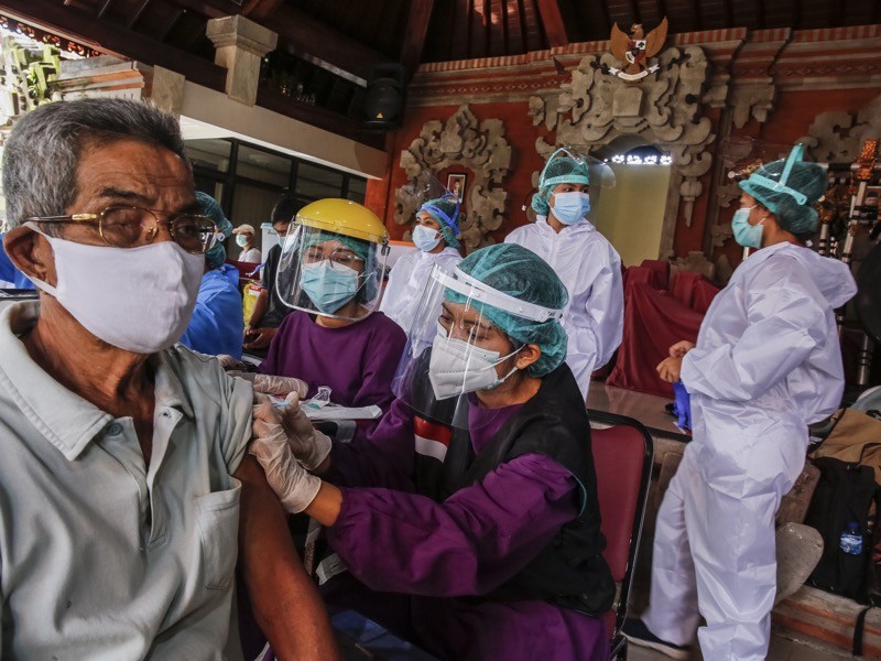 A health worker injects a dose of AstraZeneca COVID-19 vaccine during vaccination program in Sanur, Indonesia.