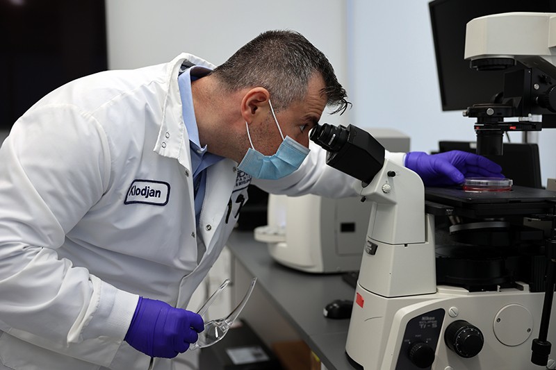 Klodjan Stafa in his lab checking on a research project through a microscope.