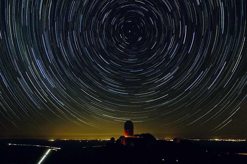An observatory at night, shown with the stars "circling" the sky from a long exposure.