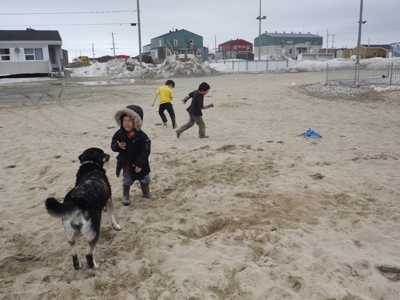 Inuit children play in the sand on a warm day.