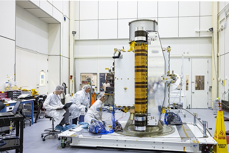 Members of the DART team at APL inspect the spacecraft in a clean room.