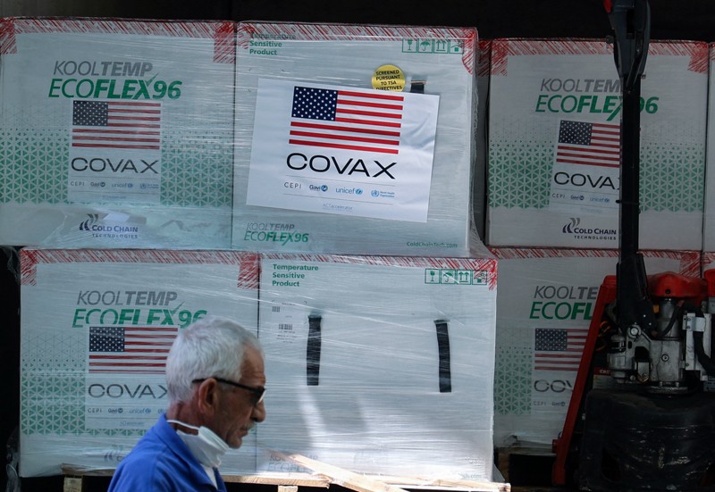 Personas descargan cajas de vacunas COVID-19 con etiquetas COVAX