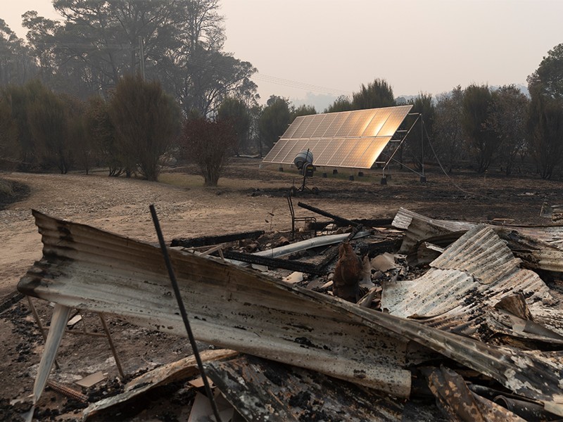 Solar panels stand amid the burnt wreckage of a property