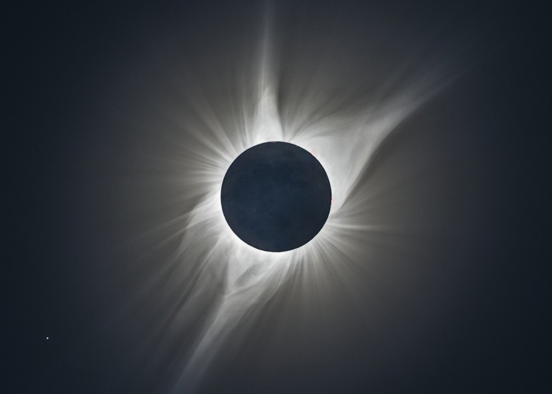 Total solar eclipse with the sun's inner corona (atmosphere) visible around the disc of the moon.