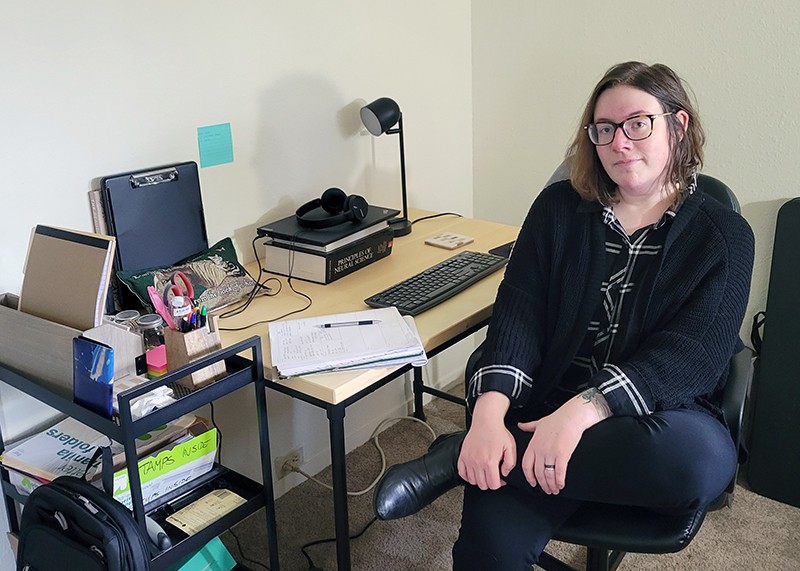 Elizabeth Aulino at her current home office, sitting in a chair in front of her desk.