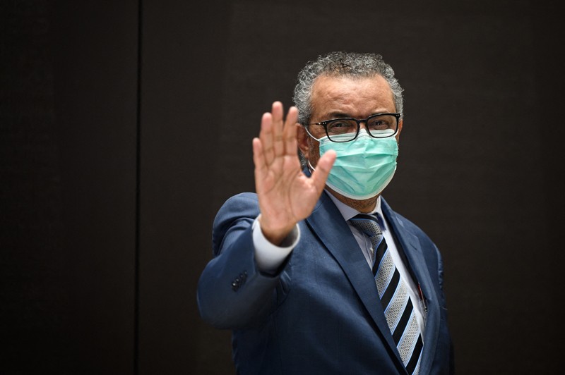 WHO Director-General Tedros Adhanom Ghebreyesus waves while wearing a face mask
