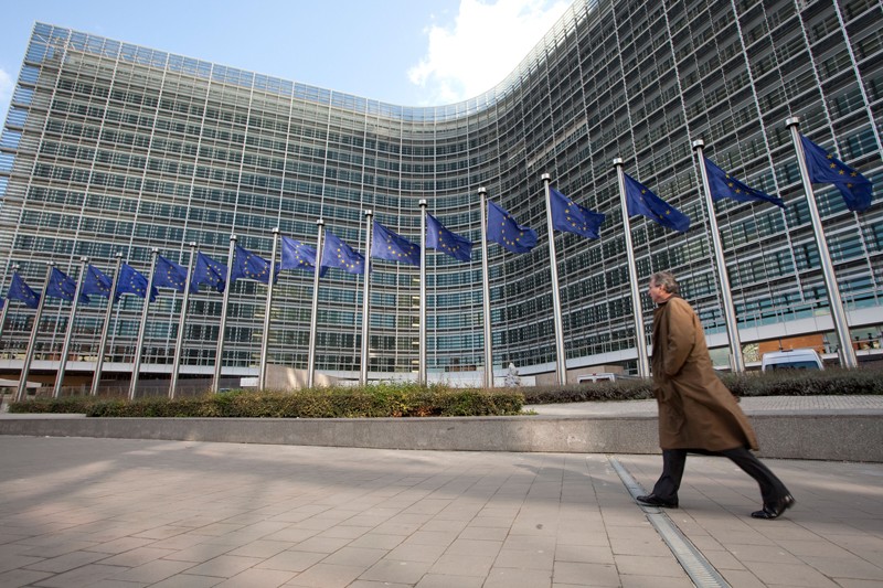 A man walks next to European flags outside the headquarters of the European Commission in Brussels