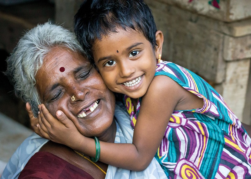 A young girl hugs the face of her grandmother
