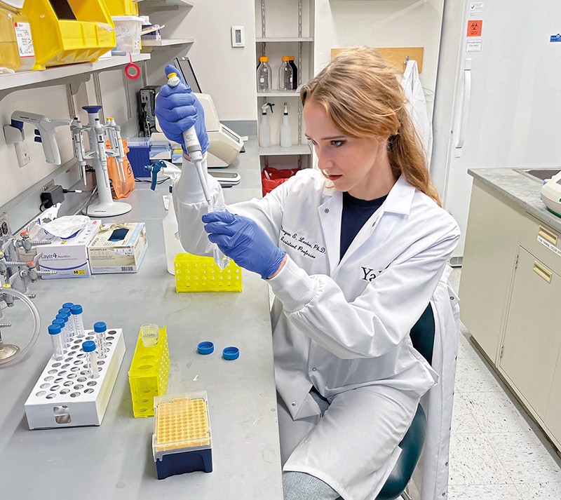 Morgan Levine sits at a lab bench using a pipette