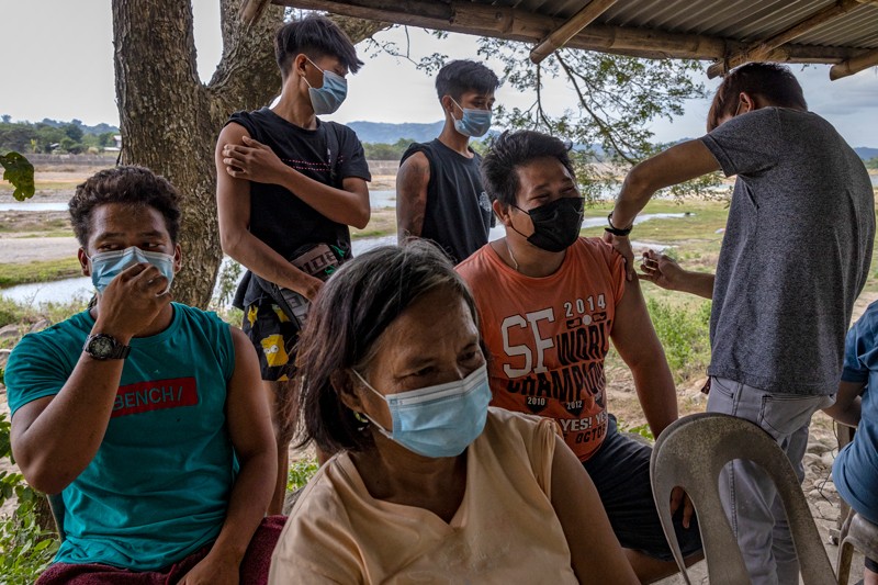 Residents of a rural village in the Philippines gather to receive a dose of COVID-19 vaccine