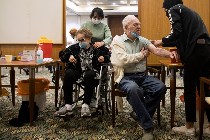 İsrail'deki bir huzurevinde yaşlı bir erkek ve kadın dördüncü doz covid-19 aşısı alıyor.