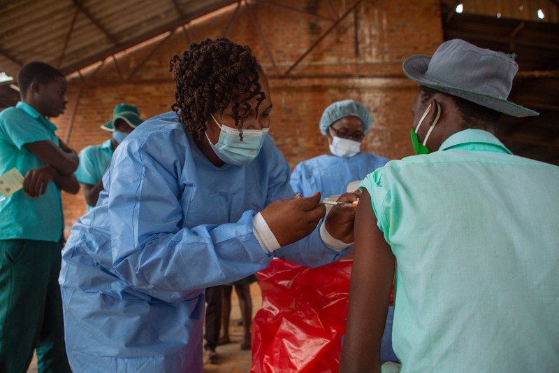 A health worker administers a COVID-19 vaccination to a teenage school student at a country school in Zimbabwe