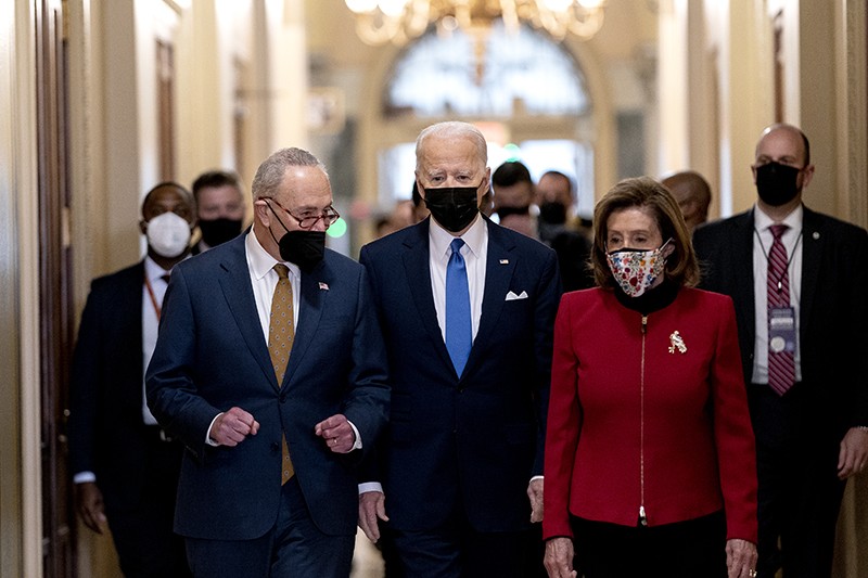 Left to right: Senator Chuck Schumer, U.S. President Joe Biden, and House Speaker Nancy Pelosi walk through the Hall of Columns.