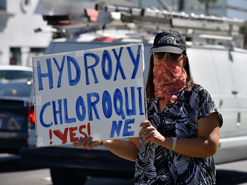 Woman holding a sign promoting using hydroxychloroquine for COVID-19.