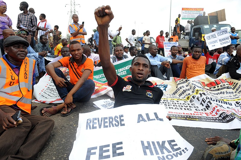 Protestors with signs against the suspension of academics in state-owned universities sit on the highway, Lagos, Nigeria 2013.