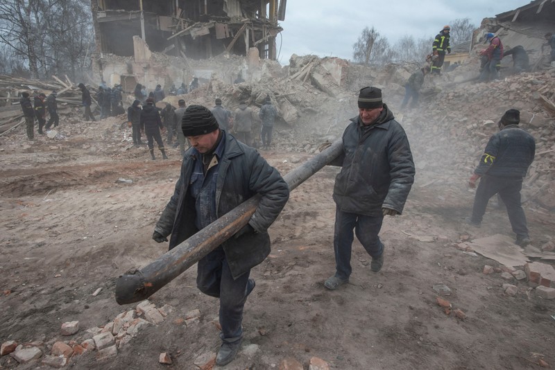 People clear debris from a damaged military base in Okhtyrka in the Sumy region, Ukraine