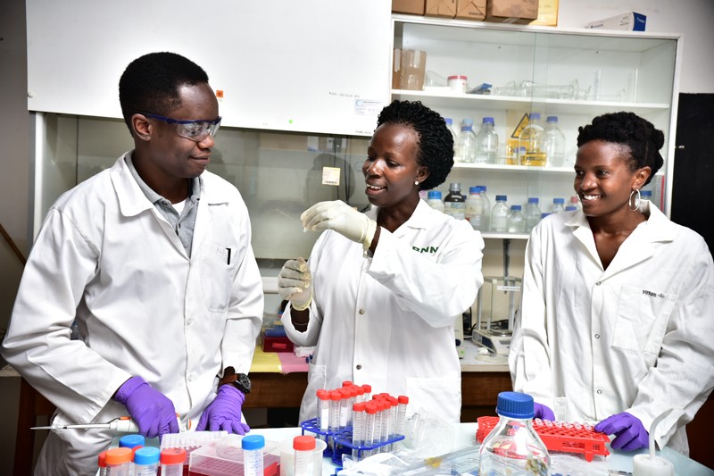 Dr. Namanya training two students in the lab