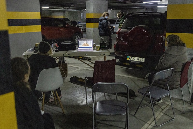 Residents watch the news on a laptop in the carpark of a large apartment block, used as a bomb shelter in Kyiv, Ukraine.